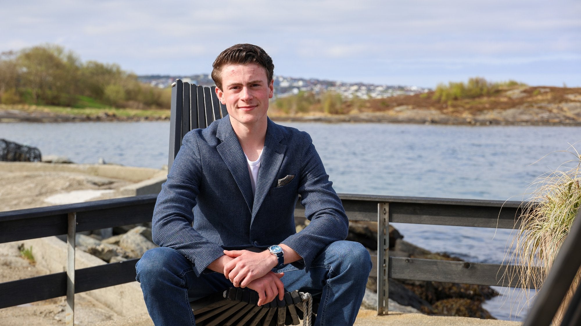 Marcus Bu Helland seated by the water in a blue jacket