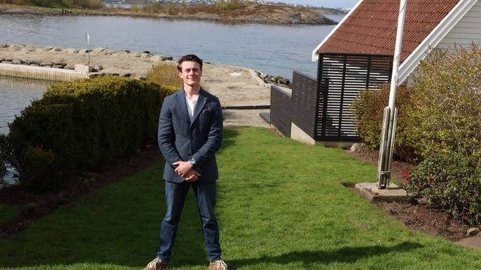 Full-length photograph of Marcus in a blue suit by the sea